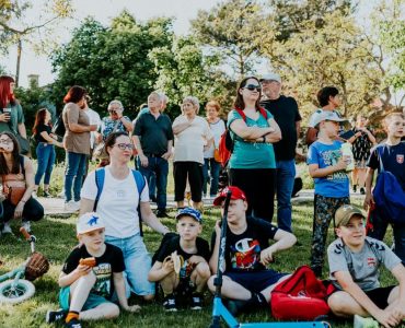 A diverse group of people enjoying a sunny day at an outdoor community event in a park setting.